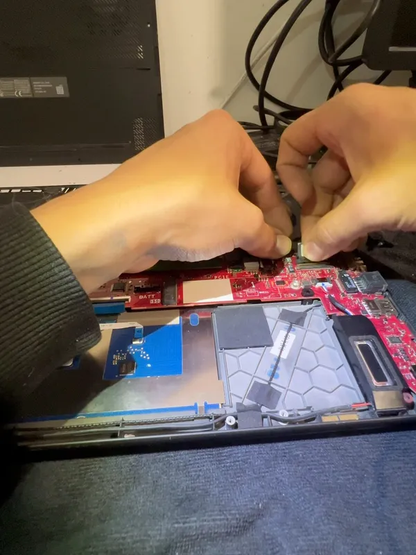 Manos trabajando sobre la placa de un portátil abierto